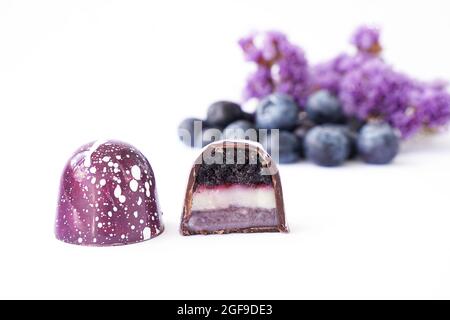 Chocolate candy in a cut on a white background. Blueberry and lavender flavor and taste. Blurred ingredients on background Stock Photo