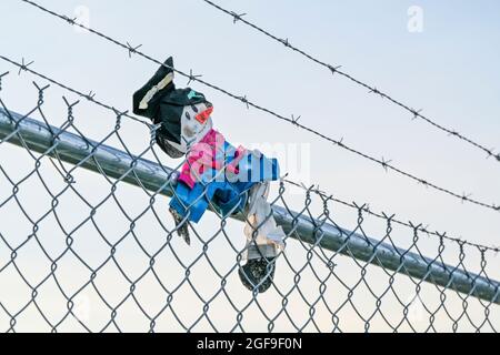 I'm outta here! toy scarecrow stuck on barbed wire fence. Stock Photo