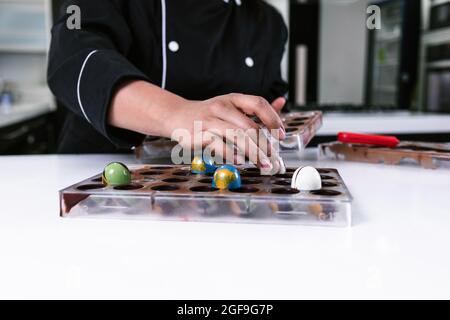 hand of latin woman pastry chef wearing black uniform in process of preparing delicious sweets chocolates at kitchen in Mexico Latin America Stock Photo