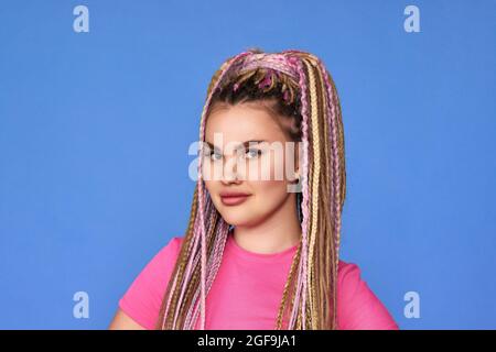 unsatisfied woman with dreadlocks on blue background. Stock Photo