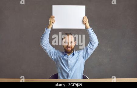 Smiling young man holding a banner above his head. Stock Photo
