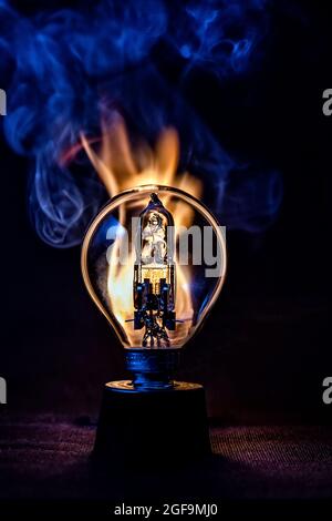 Edison style light bulb against fire and smoke in darkness Stock Photo