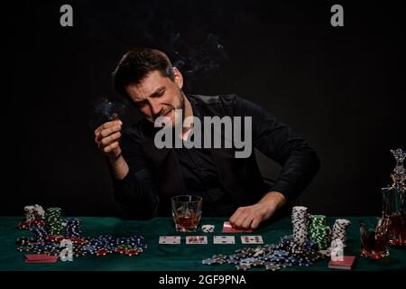 Bearded casino player man playing poker on green table Stock Photo