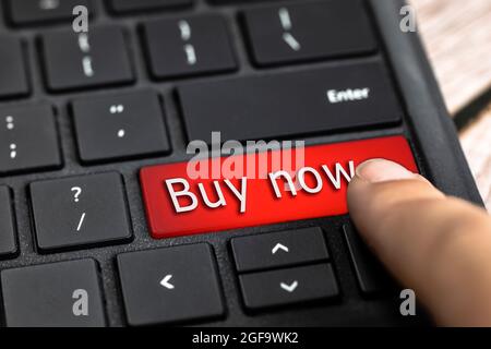 Closeup of finger on red computer keyboard key with the text Buy now in white Letters, Online shopping, technology and sale concept Stock Photo