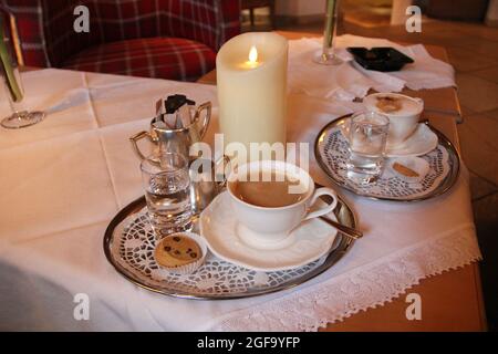 Coffee with Silver on Table with Candle Stock Photo