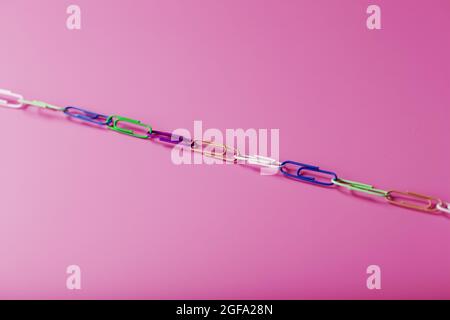 Multicolored paper clips are attached in a row on a pink background. Free space Stock Photo