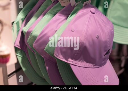 Green and pink baseball caps hanging on a rack. Stock Photo