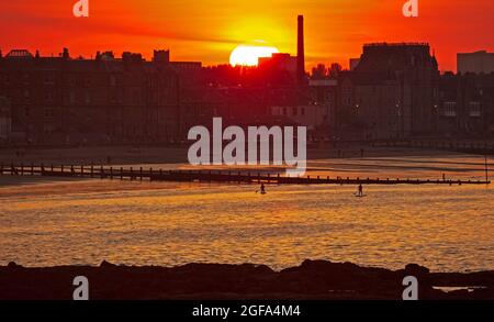 Portobello, Edinburgh, Scotland.UK weather. 24th August 2021 Stunning sunset at the seaside looking over the Firth of Forth with paddle boarders in the water towards the promenade. Credit: Arch White/Alamy Live News. Stock Photo