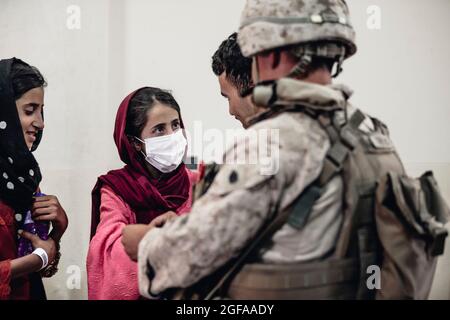 Kabul, Afghanistan. 24th Aug, 2021. A U.S. Marine assigned to Special Purpose Marine Air-Ground Task Force - Crisis Response team assists Afghan refugees at Hamid Karzai International Airport during Operation Allies Refuge August 24, 2021 in Kabul, Afghanistan. Credit: Planetpix/Alamy Live News