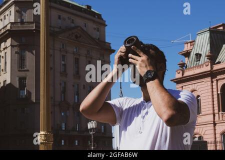 A man outdoors photographing something heading towards the sky. man with clock and photo camera in hand. photographing architecture in Buenos Aires, Stock Photo