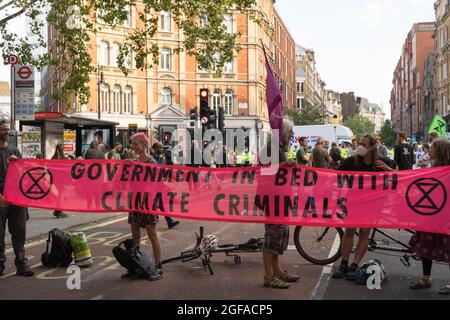 Cambridge Circus, London, UK. 24th August 2021. Climate change protesters from Extinction Rebellion sitting  at Cambridge Circus , blocking Charing Cross road along the way to Trafalgar Square. Credit: Xiu Bao/Alamy Live News Stock Photo