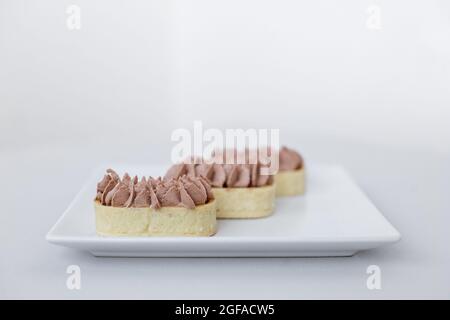 Tartlet with chocolate mousse on a white plate for catering, space for design Stock Photo