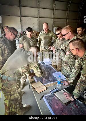 Army Maj. Joseph Genin, Task Force operations officer, briefs Battalion  Commander Lt. Col. Jacob Helgestad, company commanders, and task force staff on current operations at Hamid Karzai International Airport on August 21,  2021. With its strategic assignment at Camp Buehring, Task Force 1-194 was positioned to respond to the Noncombatant Evacuation Operation announced by the Department of State and supported by the Department of Defense.    Approximately 1,100 Soldiers from Task Force 1-194 deployed to the Middle  East in early 2021 for a nine-month mission in support of Operation Spartan Stock Photo