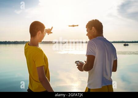 Two friends operating drone with controller standing near the river Stock Photo