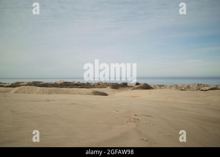 Sand dunes leading to the Pacific Ocean at Pismo Beach, on cloudy winter's day, with hazy grey mountains on the horizon Stock Photo