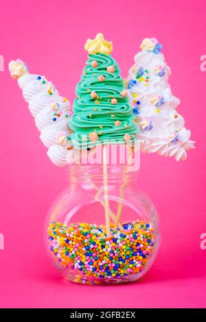 Christmas tree shaped meringue lollipops on a colorful pink background Stock Photo