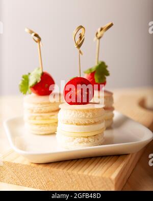 Delicious Party Snacks. Round mini sandwiches with ham and cheese decorated with cherry tomato on a bamboo stick Stock Photo
