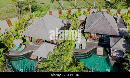 Aerial view of luxury hotel with straw roof villas and pools in ...
