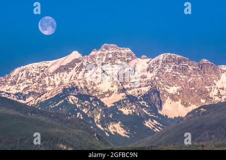 moon over peaks of the mission range above elk creek valley near condon, montana Stock Photo