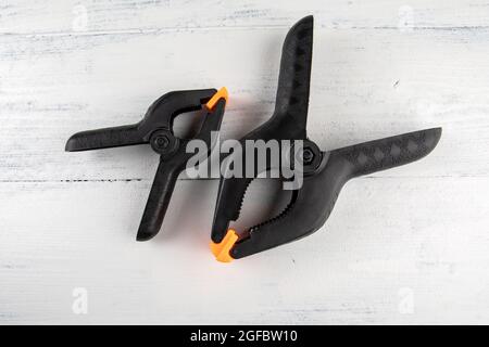 Black plastic clamps on a white wooden background. Stock Photo