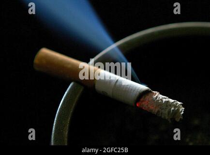 File photo dated 14/06/2007 of a cigarette burning on an ashtray. The number of young adults who smoke in England rose by a quarter in the first lockdown but more people also successfully kicked the habit, new research has suggested. Hundreds of thousands more smoked compared to before the coronavirus pandemic hit, the study funded by Cancer Research UK showed. Issue date: Wednesday August 25, 2021. Stock Photo