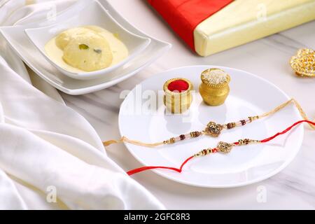 Indian Festival Raksha Bandhan with Rakhi, Sweets, Rice Grains, Kumkum and Gift. A traditional festival celebrated for the love between brother and si Stock Photo