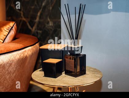 Reed diffuser and decorative boxes on the stylish table in contemporary style home interior. Home fragrance bottle with rattan sticks. Stock Photo