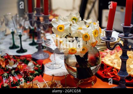 Elegant glass vase with a bouquet of daffodils to decorate the dining table. Beautiful festive table setting Stock Photo