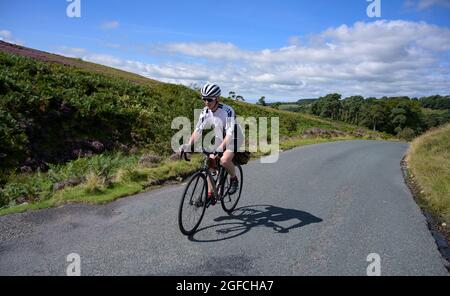 Mature male cyclist riding through the Trough of Bowland, Lancashire, UK. Stock Photo