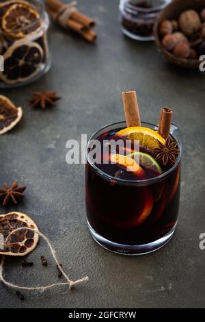Mulled wine with lime and orange slices, cinnamon and cloves, hot winter drink in a glass mug Stock Photo