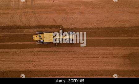 Aerial view yellow excavator building a highway, Road grader heavy earth moving, Bulldozer working at road construction. Stock Photo