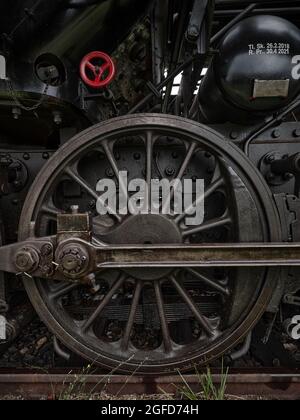 Close-up of an old steam locomotive wheel, showing vintage railway engineering, dark metal texture and industrial heritage detail. Stock Photo
