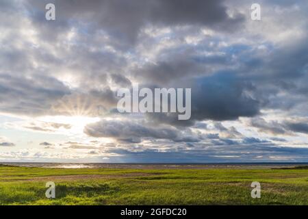 Sun rays through cloudy sky over the North Sea after storm weather at sunset Stock Photo