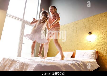 Lovely mother with cute little daughter having fun together at home. Happy young woman bonding with her parents. Parenting and childhood concept. Joy Stock Photo