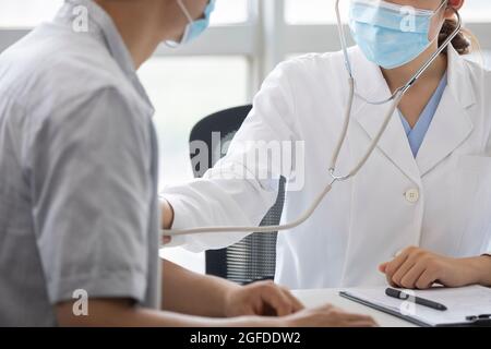 Doctor using stethoscope to examine patient Stock Photo