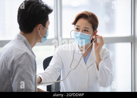Doctor using stethoscope to examine patient Stock Photo