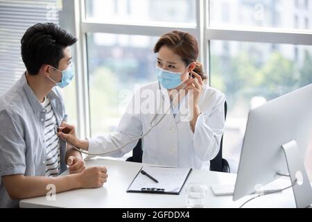 Doctor using stethoscope to examine patient Stock Photo