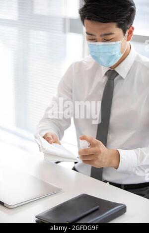 Young businessman using disinfectant in office Stock Photo