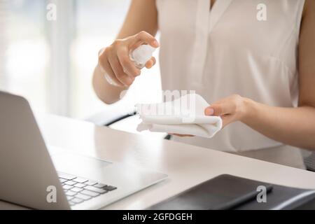 Young businesswoman using disinfectant in office Stock Photo