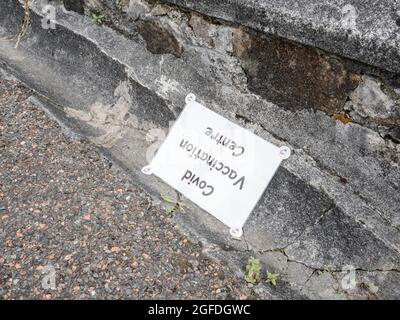 Covid 19 Vaccination Centre sign lying on the ground. Possible metaphor for anti-vaxxers, anti-vax messaging, Covid UK resistance. Stock Photo