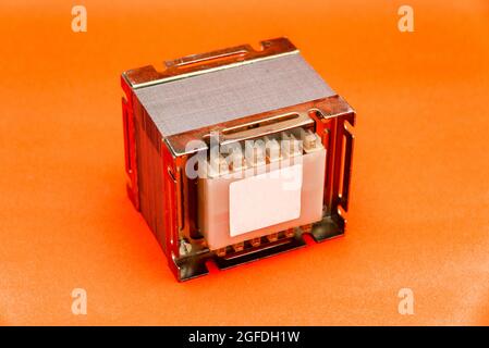 Electrical transformer (square type) for mains voltage reduction isolated on red background Stock Photo
