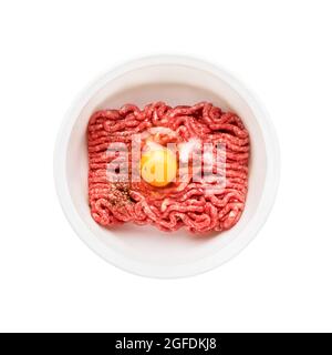 Raw ground beef, minced beef with egg and salt in a bowl isolated over white background. Top view Stock Photo