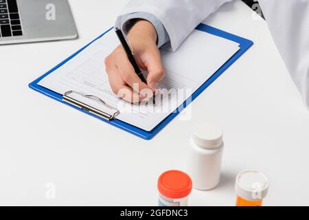 cropped view of doctor writing prescription near containers with medication, medical cannabis concept Stock Photo