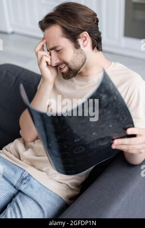 Side view of man suffering from headache while holding mri scan Stock Photo