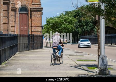 NEW ORLEANS, LA, USA - MAY 22, 2021: Bicyclist riding on the sidewalk rather than the street in the Central City neighborhood Stock Photo