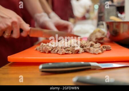 Chef cuts up meat on a cutting board with a sharp knife Stock Photo by  wirestock
