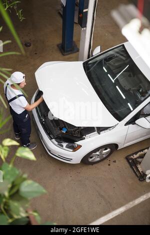 Vertical top view shot of a car service worker repairing the car at the garage Stock Photo