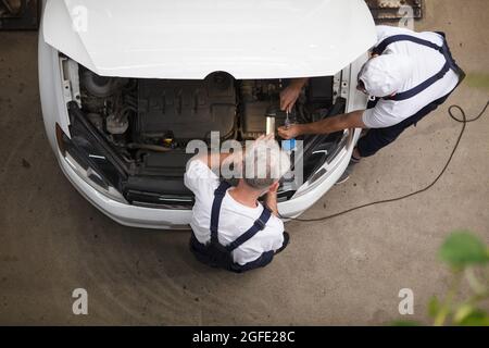 Top view shot of car repairment working under the hood of a car at the workshop Stock Photo