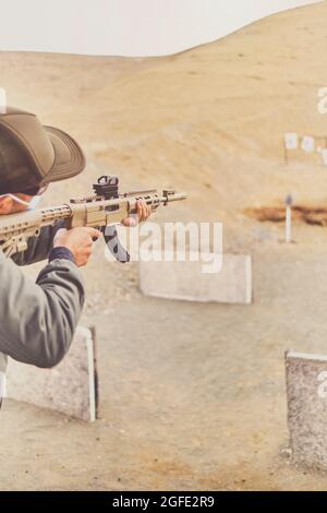 Men practicing shooting with a assault rifle at target. Selective Focus Stock Photo