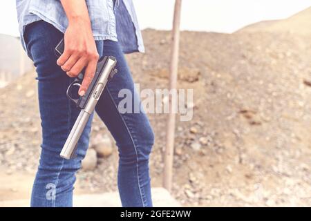 Gun in the hands of a girl, close-up arms. Stock Photo